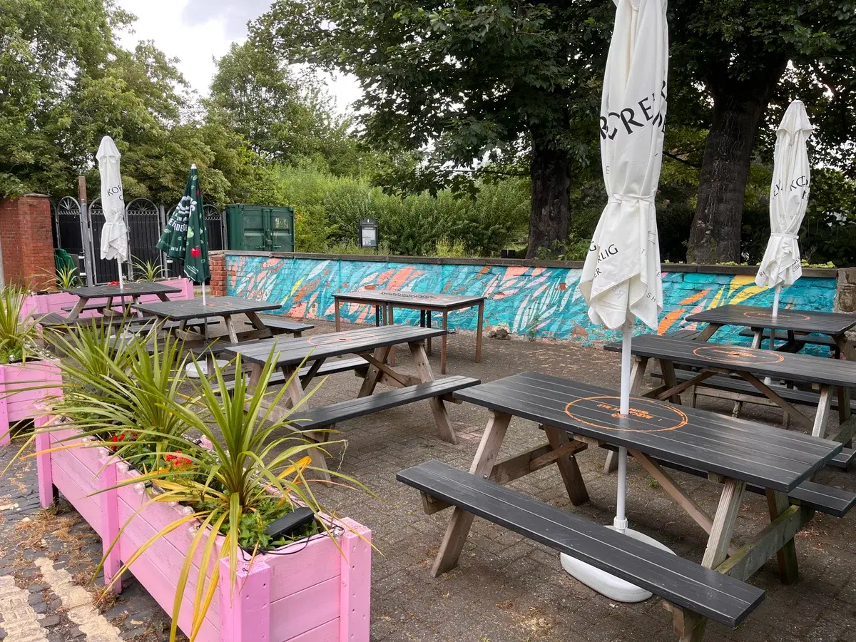 Barca Art Bar's beer garden with picnic tables, umbrellas and a painted mural wall